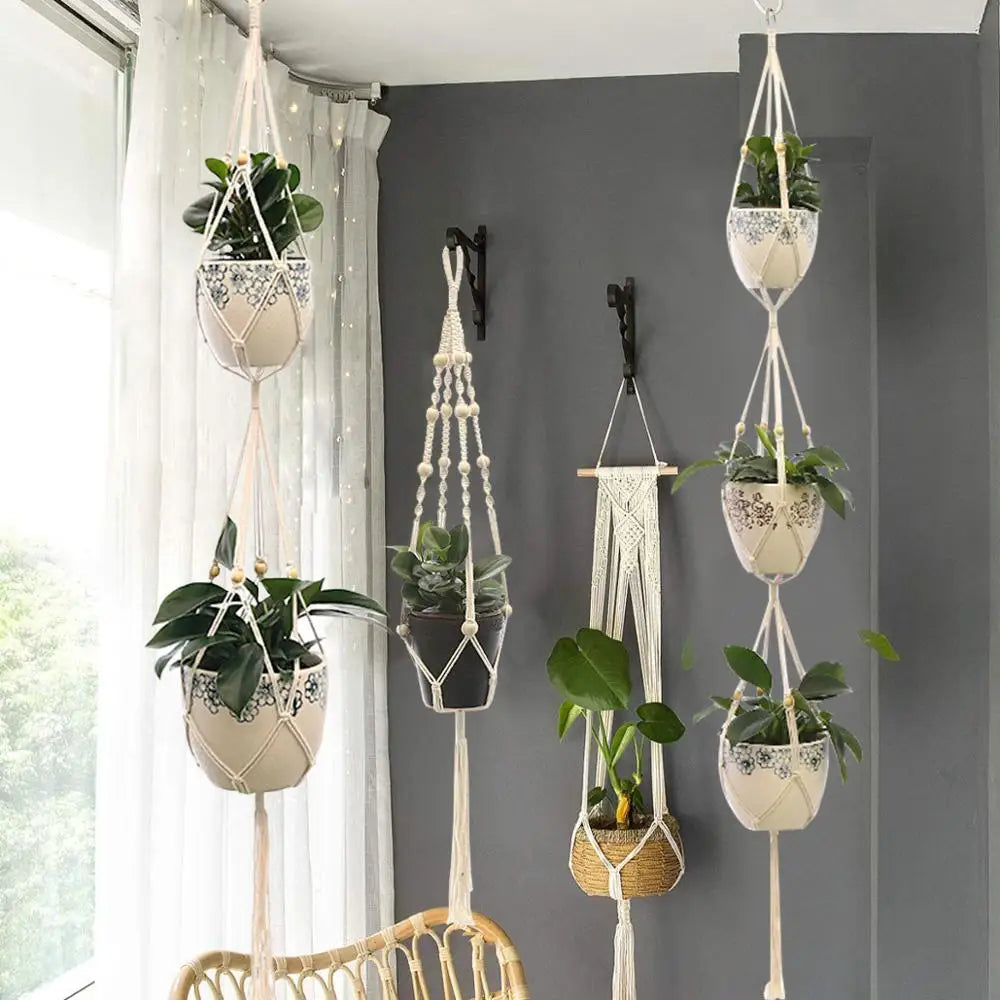 Des porte-plantes suspendus en macramé ornent un coin lumineux.
Les motifs complexes du macramé mettent en valeur la verdure des plantes.
Trois suspensions en macramé à plusieurs niveaux attirent le regard.
Une ambiance bohÚme et naturelle se dégage de cet arrangement.