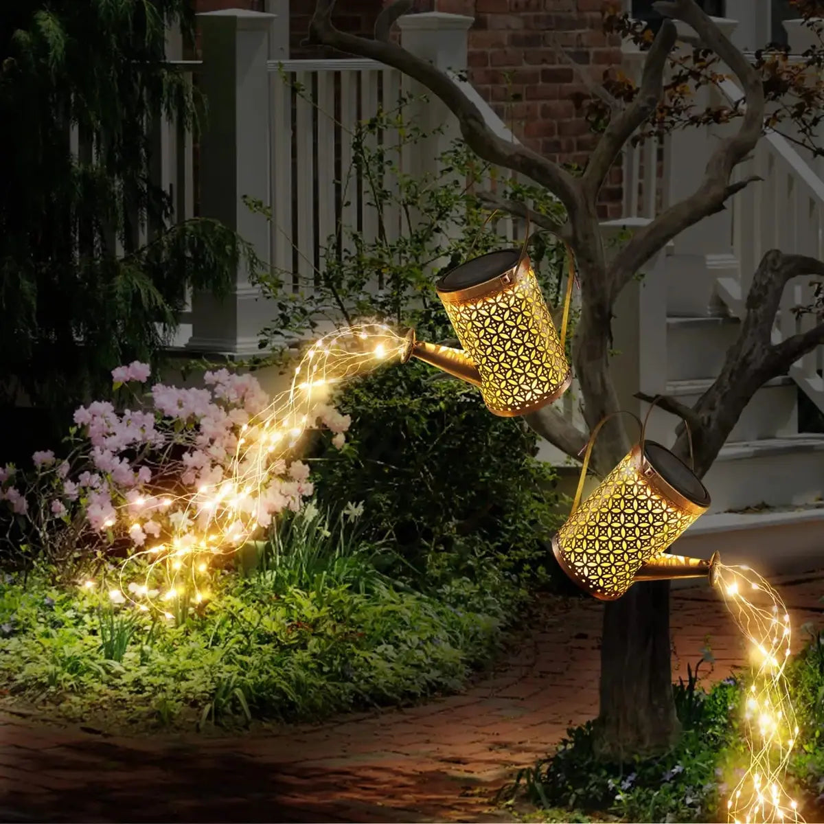 La Lampe solaire pour le jardin-Arrosoir suspendu à une branche diffuse des guirlandes lumineuses chaudes, créant un effet féerique et charmant pour la décoration extérieure près de la maison.