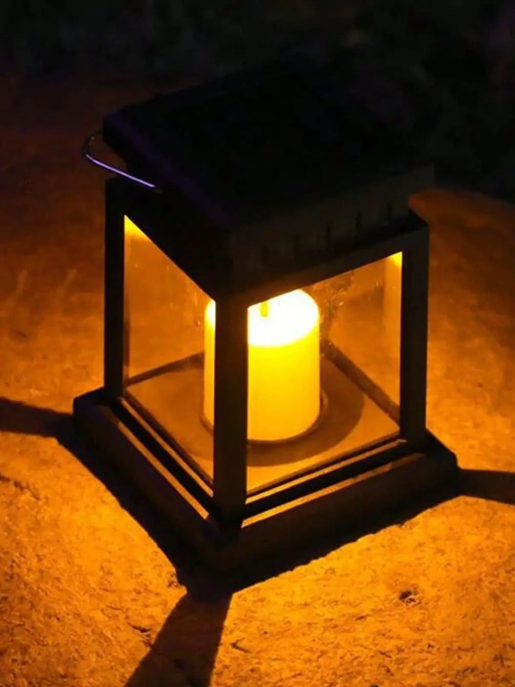 Une bougie allumée brille à l'intérieur de la Lampe solaire jardin haut de gamme-Classic-Solar™, projetant une lumière jaune chaude et des ombres douces sur une surface en pierre dans un cadre sombre.
