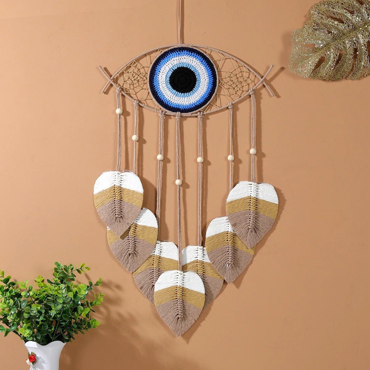 Un macrame attrape-rĂȘves en forme d'Ćil bleu vibrant, ornĂ© de plumes dĂ©coratives
Le macramé complexe crée une texture riche et un design captivant.
Des perles de bois accentuent les cordes pendantes, ajoutant une touche naturelle.