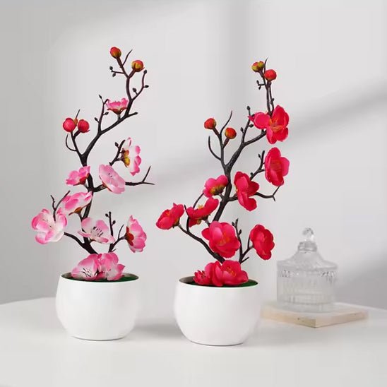 Deux élégantes plante artificielle de cerisier en fleurs, roses et rouges, en pots blancs.