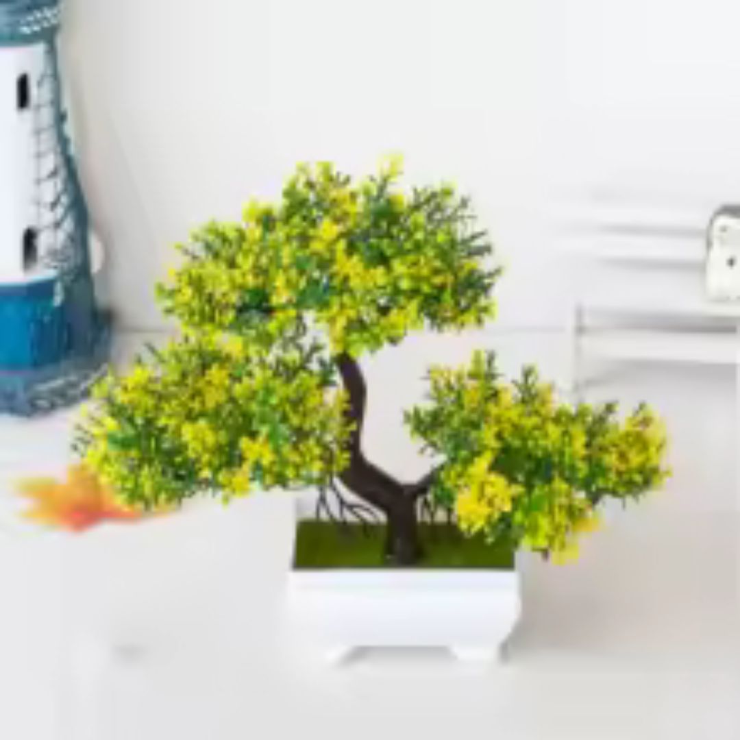 Sur une surface blanche, on aperçoit une plante artificielle imitant un petit arbre.
Ses feuilles, d'un vert vif parsemé de jaune, donnent une touche de fraîcheur.
La plante artificielle est placée dans un pot carré blanc et épuré.
À l'arrière-plan flou, on distingue d'autres objets décoratifs.
Cette petite plante artificielle apporte une note décorative sans nécessiter d'entretien.