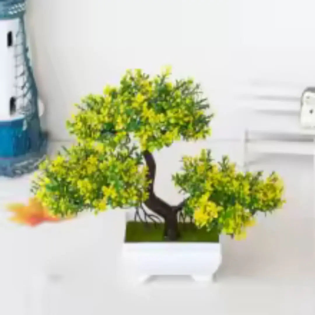 Sur une surface blanche, on aperçoit une plante artificielle imitant un petit arbre.
Ses feuilles, d'un vert vif parsemé de jaune, donnent une touche de fraîcheur.
La plante artificielle est placée dans un pot carré blanc et épuré.
À l'arrière-plan flou, on distingue d'autres objets décoratifs.
Cette petite plante artificielle apporte une note décorative sans nécessiter d'entretien.