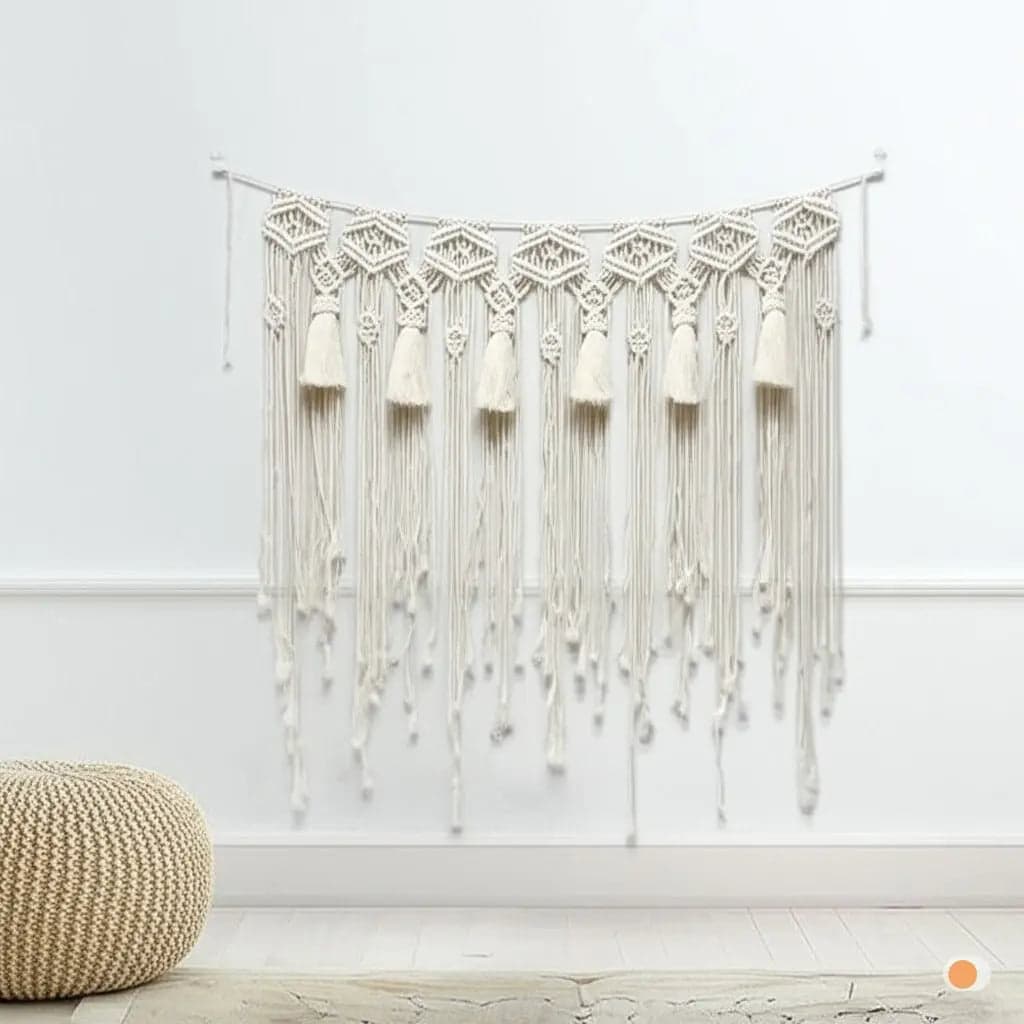 Rideau macramé décoratif en coton beige.
Design bohème avec des motifs géométriques et des franges.
Suspendu sur un mur blanc, ajoutant une touche artisanale et chaleureuse.
Présenté dans un intérieur épuré avec un pouf en rotin et un sol clair.