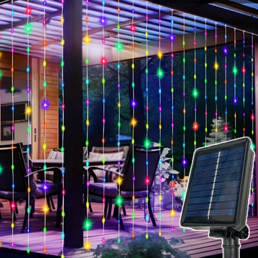 La terrasse extérieure est dotée du rideau-guirlande solaire extérieur de Lumière heureuse, affichant des lumières LED colorées qui créent une ambiance vibrante, alimentées par le panneau solaire au premier plan.