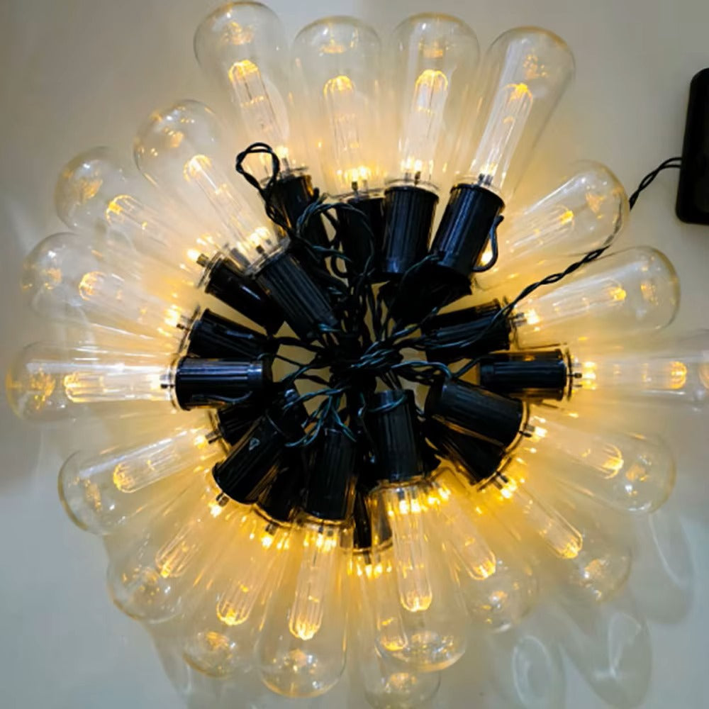La guirlande solaire | SolarZen est composée de plusieurs ampoules à filament apparentes avec des douilles noires qui émettent une lueur jaune chaude. Entrelacées de cordons noirs, cette disposition circulaire crée une ambiance extérieure enchanteresse sur toute surface plane.
