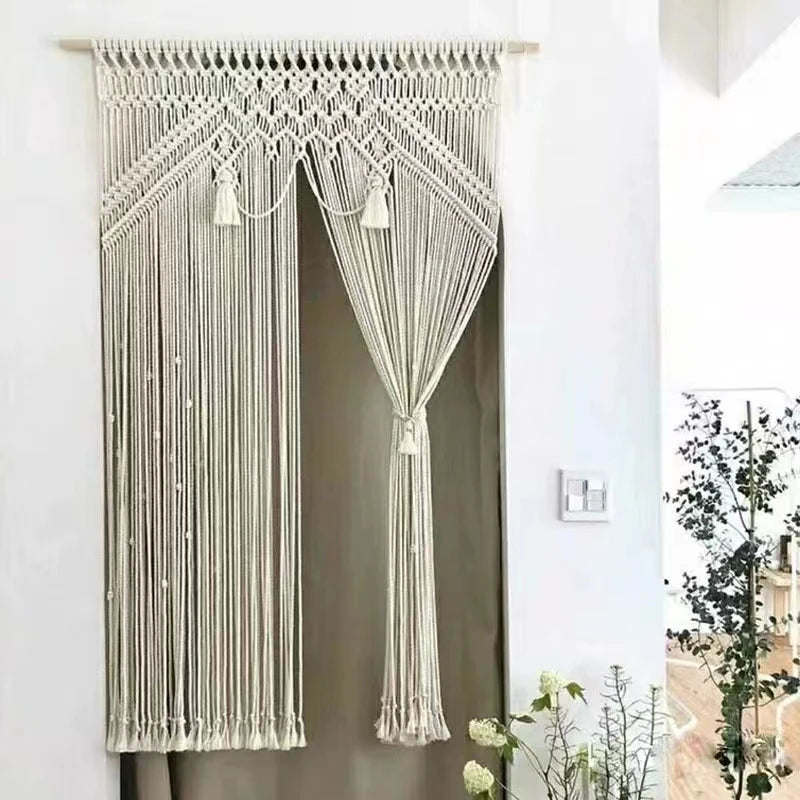 Rideau macramé artisanal complexe suspendu à une tringle en bois.
Le design présente des motifs noués décoratifs et des franges tombantes.
Il laisse entrevoir légèrement la lumière à travers ses fils de coton crème.
Ajoute une touche bohème et texturée à la décoration intérieure.