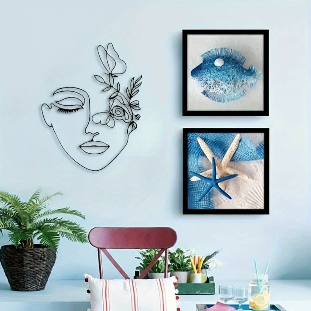 Decors murale metal visage fleuri, encadrée de tableaux marins et plante verte.