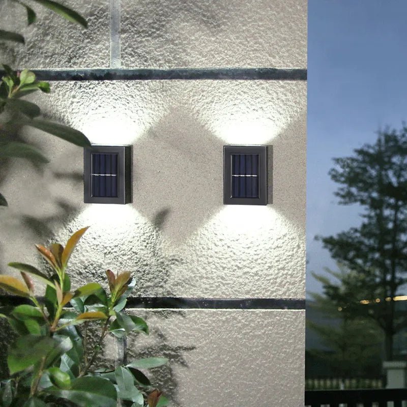 Deux élégantes Lampes solaires jardin haut de gamme. illuminent un mur extérieur texturé au crépuscule.