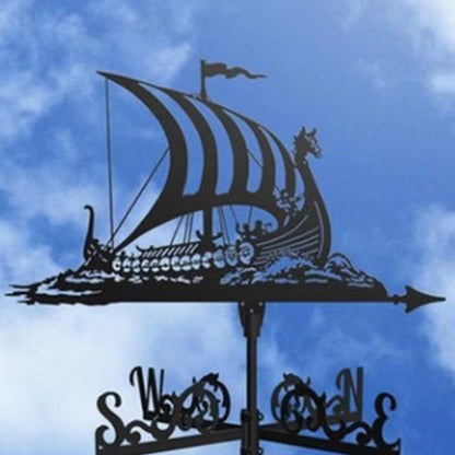 La « Girouette de jardin-Galion » représente la silhouette d'un bateau viking aux voiles rayées, ornée d'une proue à tête de dragon et de figures de pont, servant d'indicateur de ventilation. Les points cardinaux sont élégamment affichés en dessous, créant une décoration extérieure raffinée sur fond de ciel bleu nuageux.