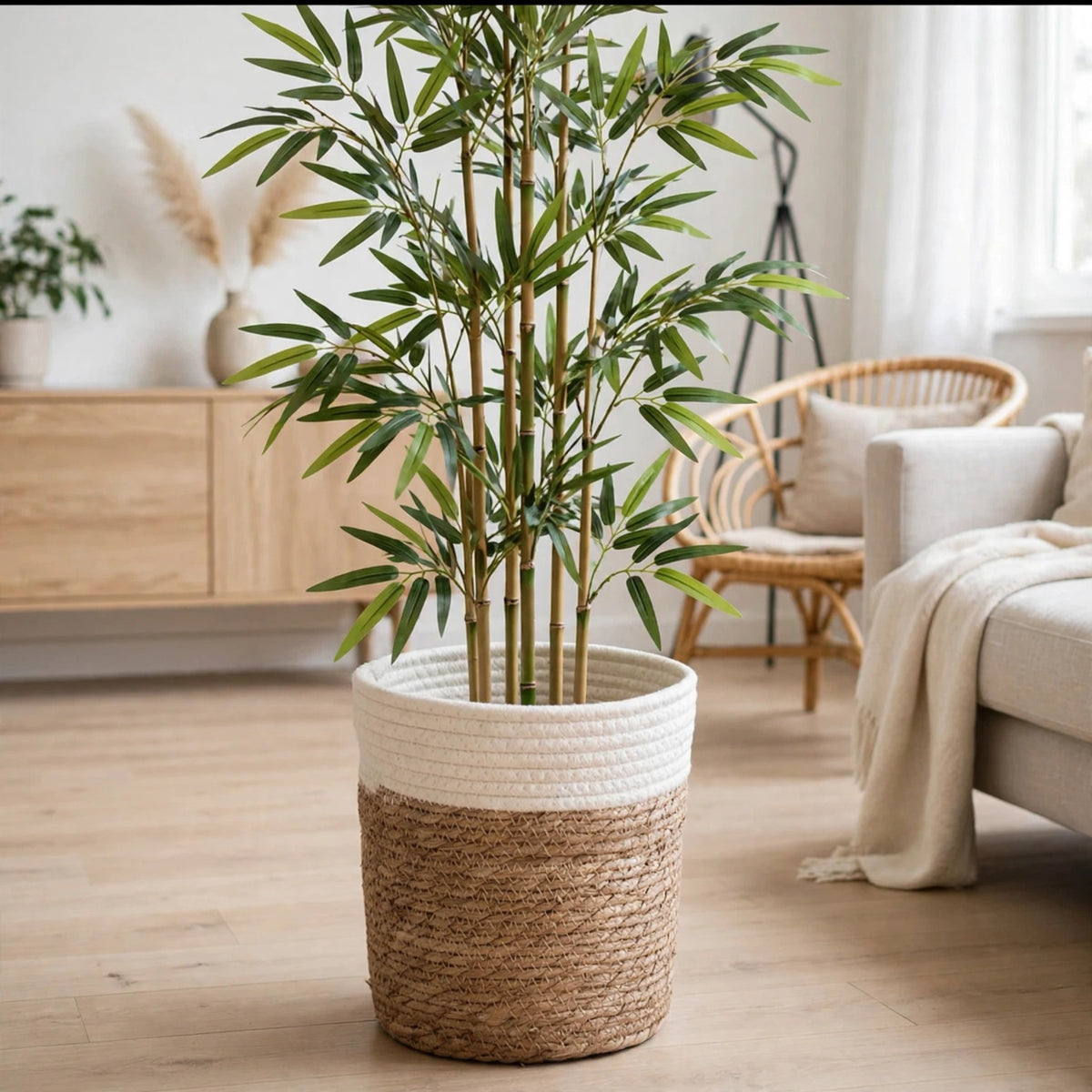 Bambou artificiel dans un cache pot blanc posé sur un parquet clair