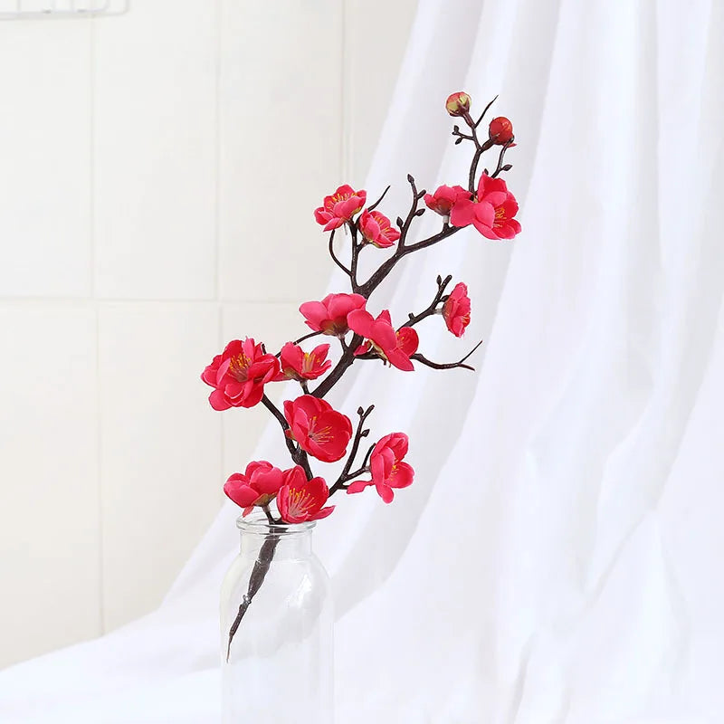 Superbe branche de cerisier, plante artificielle, avec fleurs roses vives dans un vase.