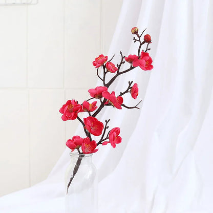 Superbe branche de cerisier, plante artificielle, avec fleurs roses vives dans un vase.
