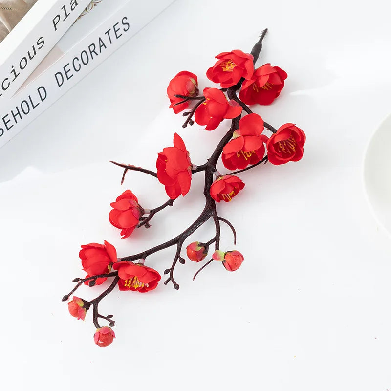 Branche de prunier en fleurs rouges, plante artificielle décorative, sur fond blanc.