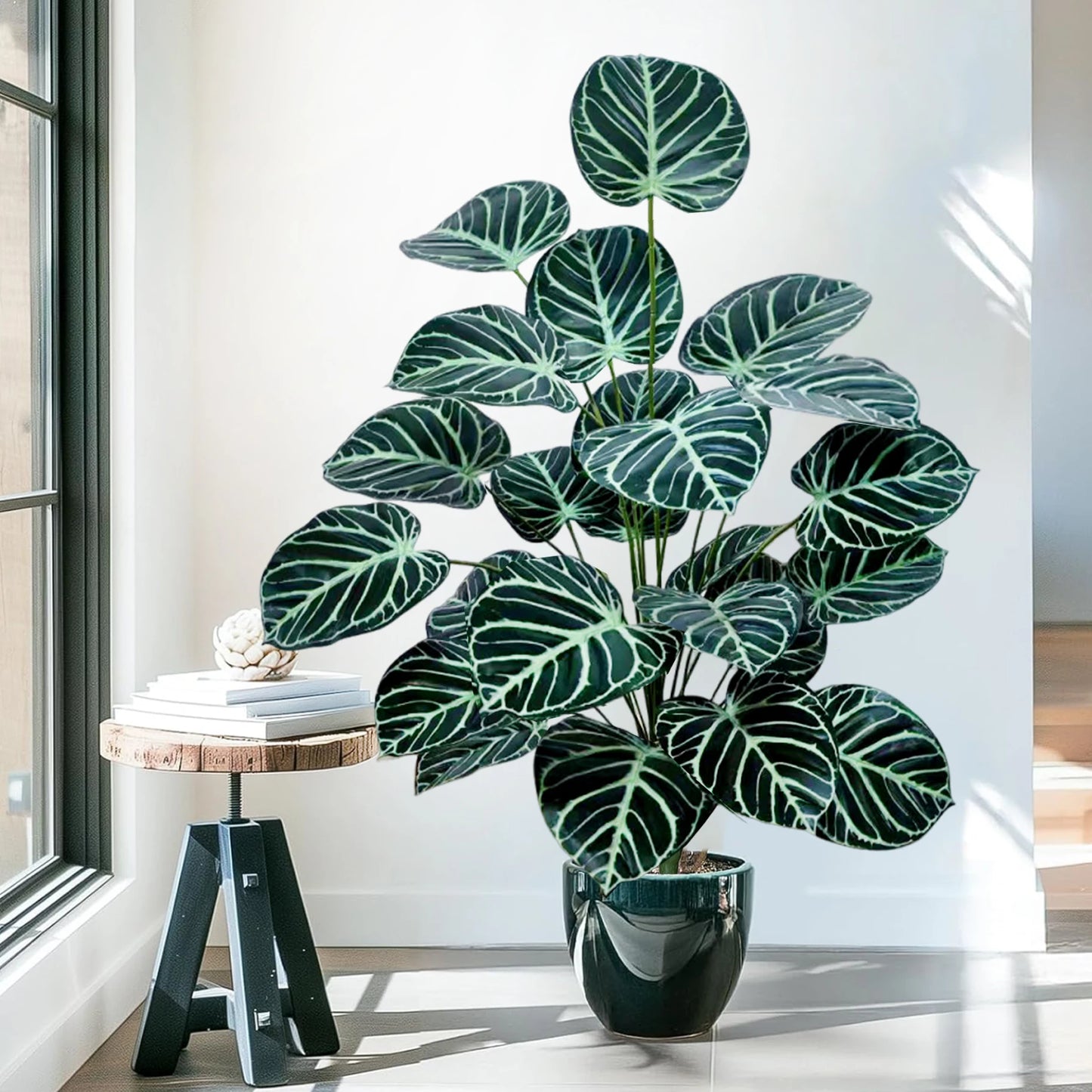 Grande plantes artificielles comme des vraies. ressemblant à un Calathea avec des feuilles vertes striées de blanc, placée dans un pot noir élégant près d'une fenêtre ensoleillée.
