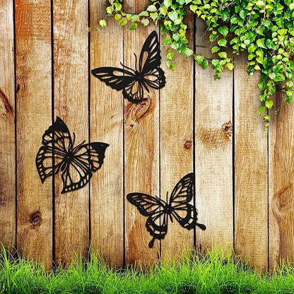 Trois Decoration Murale Papillons noirs stylisés ornent une clôture en bois rustique.