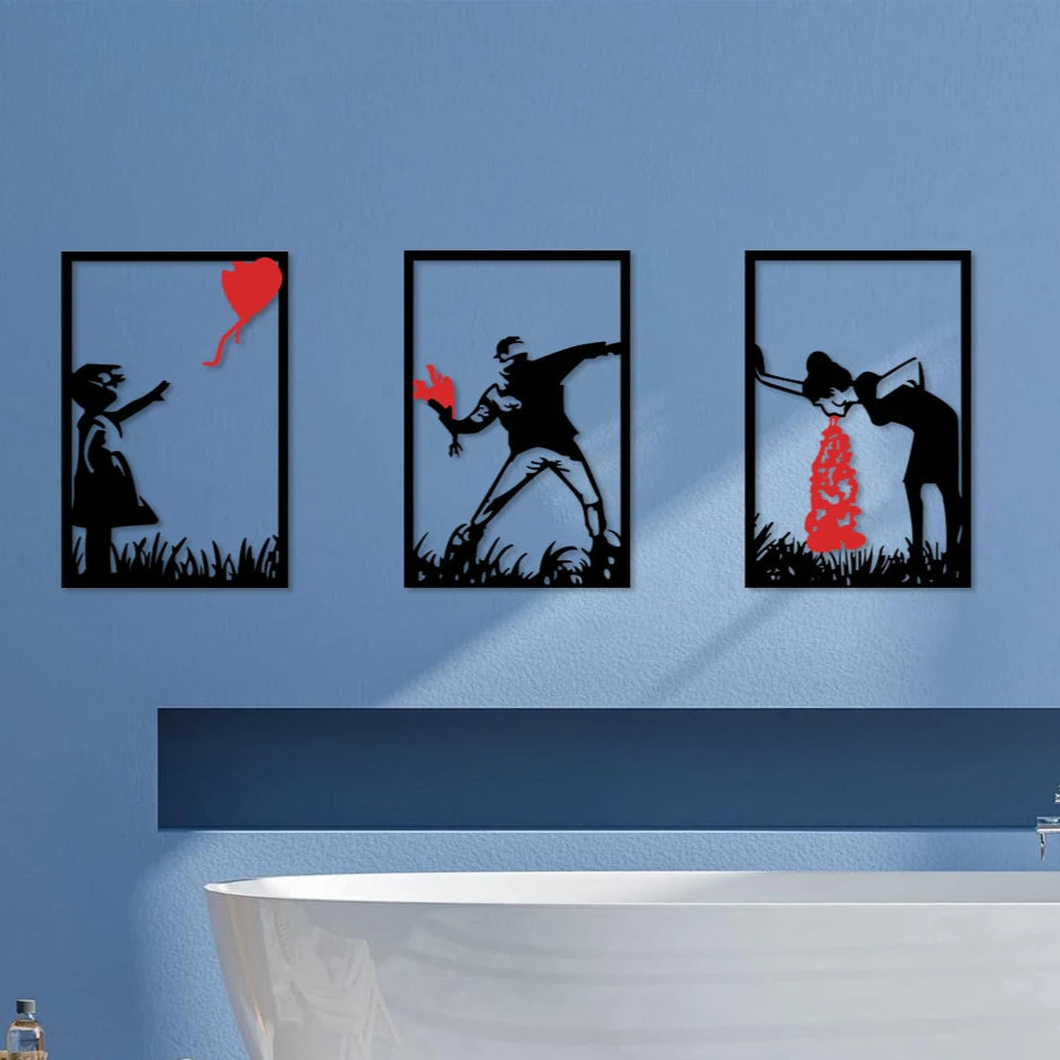 Trois Decoration murale pour salon noires et rouges inspirées de Banksy au-dessus d'une baignoire blanche.