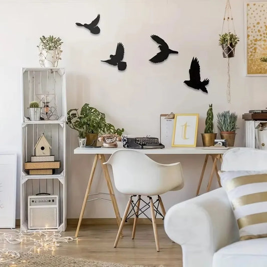 Quatre oiseaux noirs Decorations Murales Extérieures en vol, égayant un mur blanc au-dessus d'un bureau épuré.