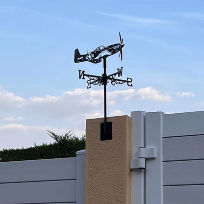 Une charmante Girouette de jardin-Galion orne un pilier beige, faisant office à la fois de décoration extérieure élégante et de girouette de jardin pratique. Le ciel clair, avec quelques nuages, forme un arrière-plan parfait sur le mur clair.
