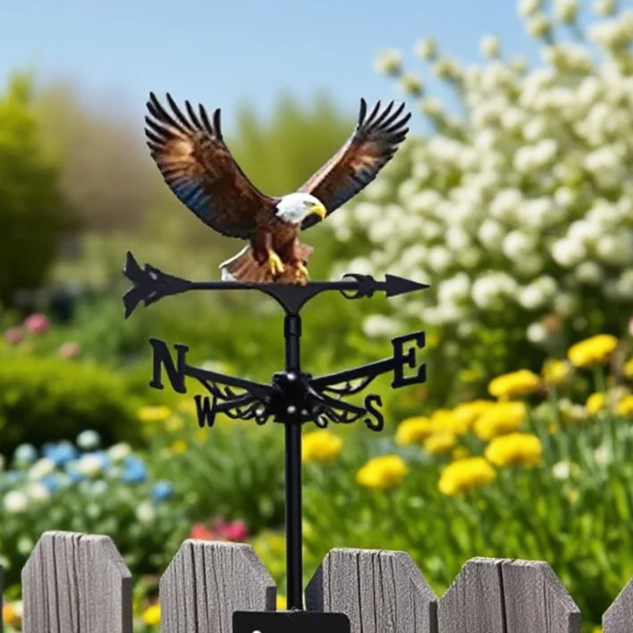 Girouette oiseau aigle sur clôture de jardin fleurie par une journée ensoleillée.