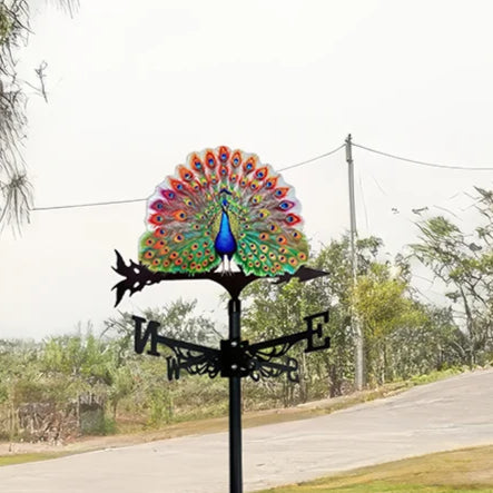 Girouette oiseau en forme de paon vibrant sur fond extérieur verdoyant.