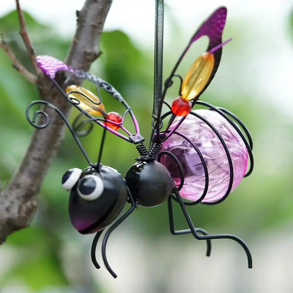 Gros plan décoration jardin abeille métal détails artisanaux ailes verre teiné violet rose ambre yeux expressifs finitions qualité