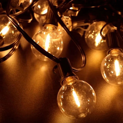 Gros plan sur une guirlande lumineuse ronde aux filaments jaune-orange chauds sur fond sombre. La guirlande solaire extérieure puissante | Ambiance Enchantée partiellement emmêlée crée une atmosphère ambiante et chaleureuse et ajoute une touche dambiance magique.