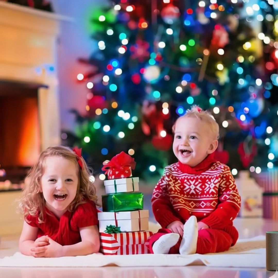 Deux enfants joyeux en rouge devant un sapin de Noël illuminé avec Guirlande Lumineuse