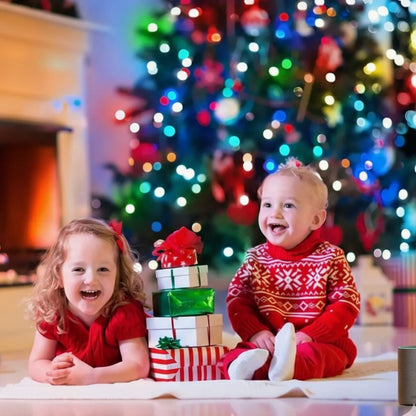 Deux enfants joyeux en rouge devant un sapin de Noël illuminé avec Guirlande Lumineuse
