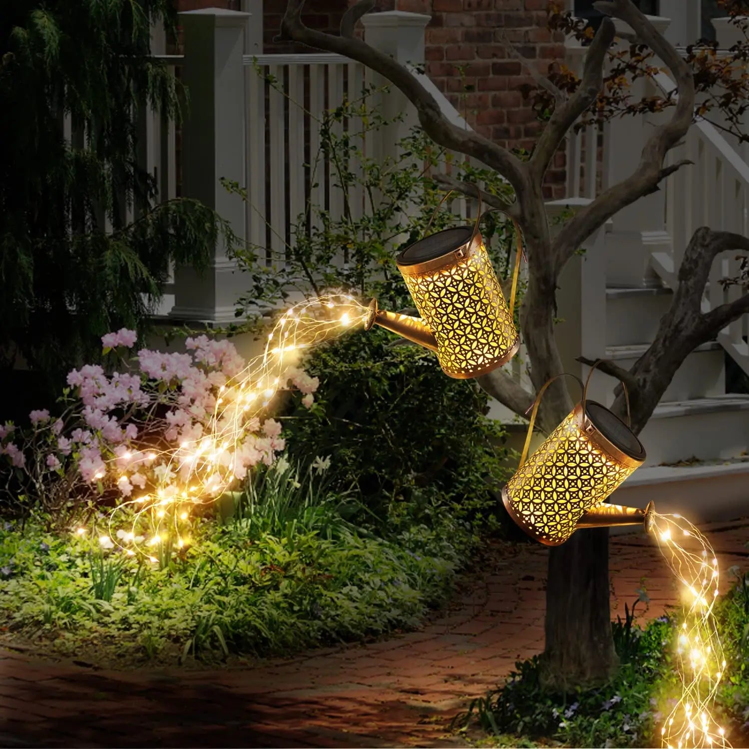 La Lampe solaire pour le jardin-Arrosoir suspendu à une branche diffuse des guirlandes lumineuses chaudes, créant un effet féerique et charmant pour la décoration extérieure près de la maison.