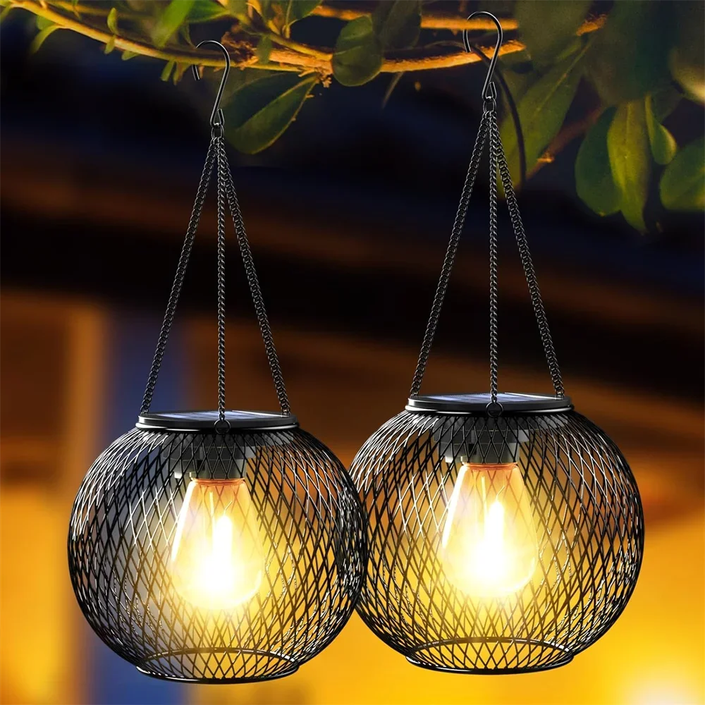La lampe solaire jardin haut de gamme comprend deux lanternes aux lumières brillantes enfermées dans des cadres sphériques en maille noire, créant une ambiance de jardin chaleureuse et invitante lorsqu'elles sont élégamment suspendues à l'extérieur à des branches d'arbres.
The Lanterne solaire suspendue | Ambiance features two lanterns with glowing lights encased in spherical black mesh frames, creating a warm and inviting garden ambiance when elegantly suspended outdoors from tree branches.