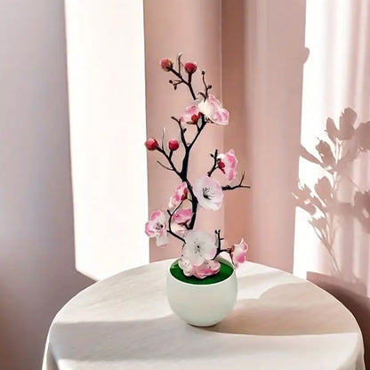 Plante artificielle fleurie, branches sombres, délicates fleurs roses, pot blanc, lumière douce.