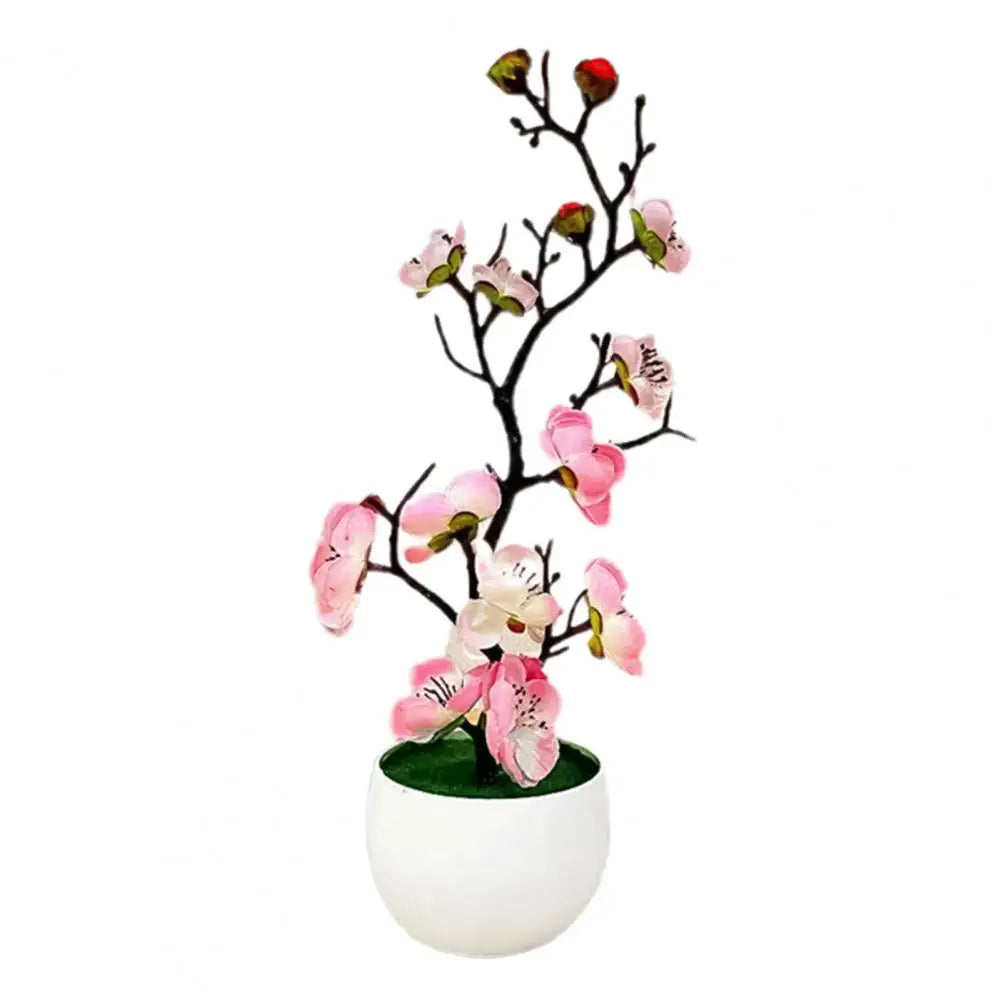 Plante artificielle fleurie rose en pot blanc sur livre. Décoration intérieure.
