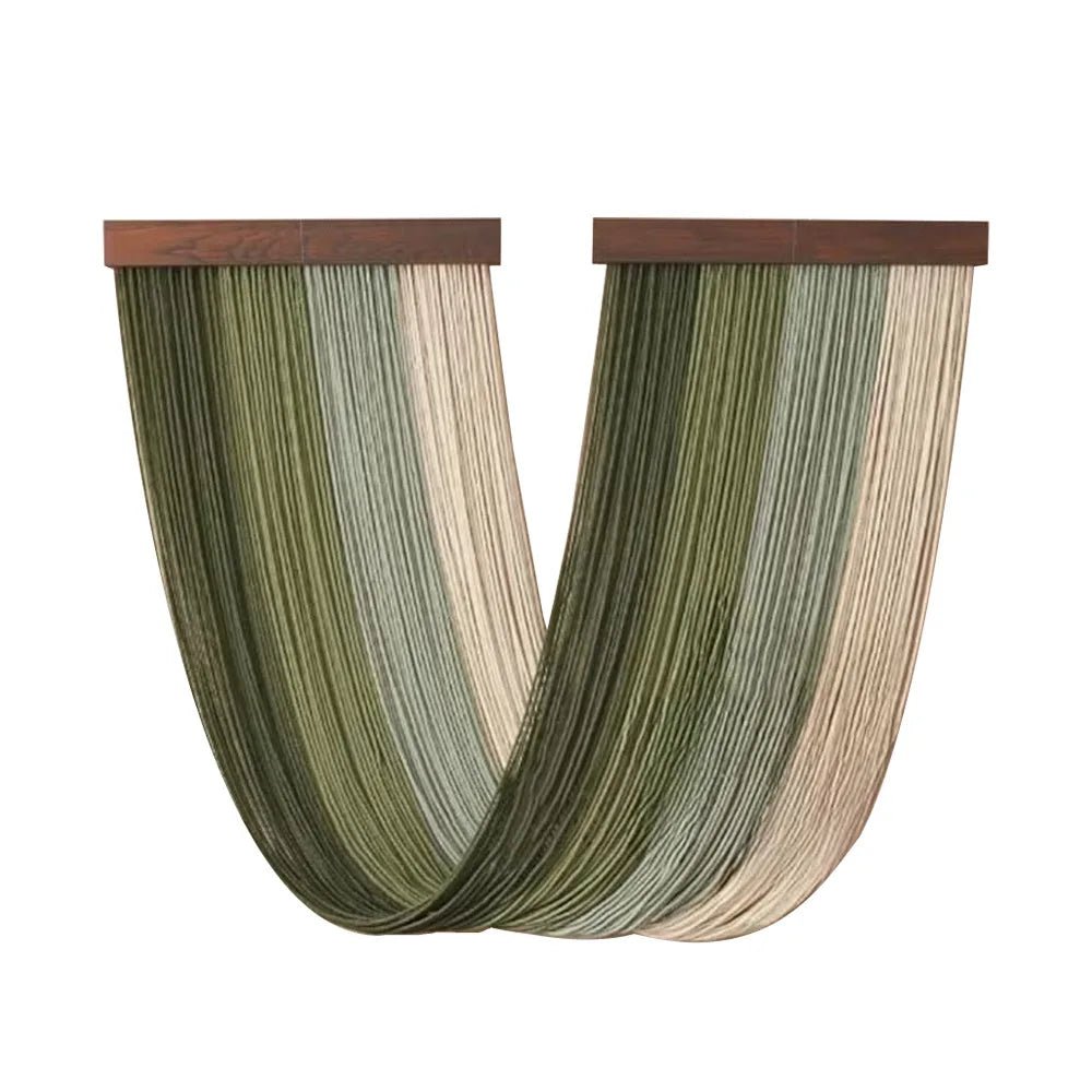 Rideaux décoratifs en macramé suspendus à deux supports en bois foncé. Les fils vert sauge, vert olive et beige crème créent un motif rayé vertical ondulant doucement vers le bas. L'artisanat délicat et les tons naturels apportent une touche bohème et élégante à la décoration intérieure.