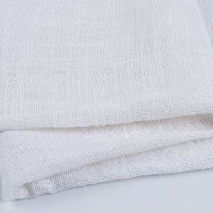 Chemin de table blanc en gaze naturel, large et polyvalent, posé sur une table élégante pour décoration raffinée.