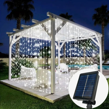 Une pergola extérieure blanche est éclairée par le rideau solaire extérieur « Lumière heureuse », qui projette une lumière chaleureuse. À l'intérieur, des chaises blanches et une table sont posées sur un sol carrelé. Des palmiers et une piscine constituent la toile de fond, avec une image en médaillon montrant un panneau solaire alimentant la lumière extérieure.