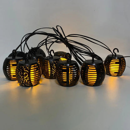 La guirlande extérieure solaire Flamme est composée de lanternes noires ornées de motifs complexes, émettant des lumières jaunes chaudes pour créer un effet flamme. Parfaites pour l'éclairage extérieur, ces lumières extérieures projettent une douce lueur sur n'importe quel fond neutre.