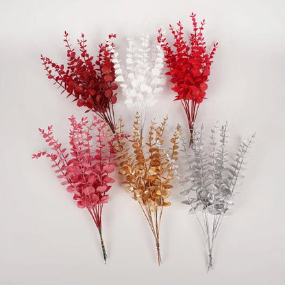 Six bouquets de plantes artificielles comme des vraies-Feuilles D'eucalyptus Doré "Feuilles d'eucalyptus doré" sont disposées sur fond blanc. Leurs branches rouges, blanches, roses, dorées et argentées apportent une touche élégante et vibrante à la décoration intérieure.