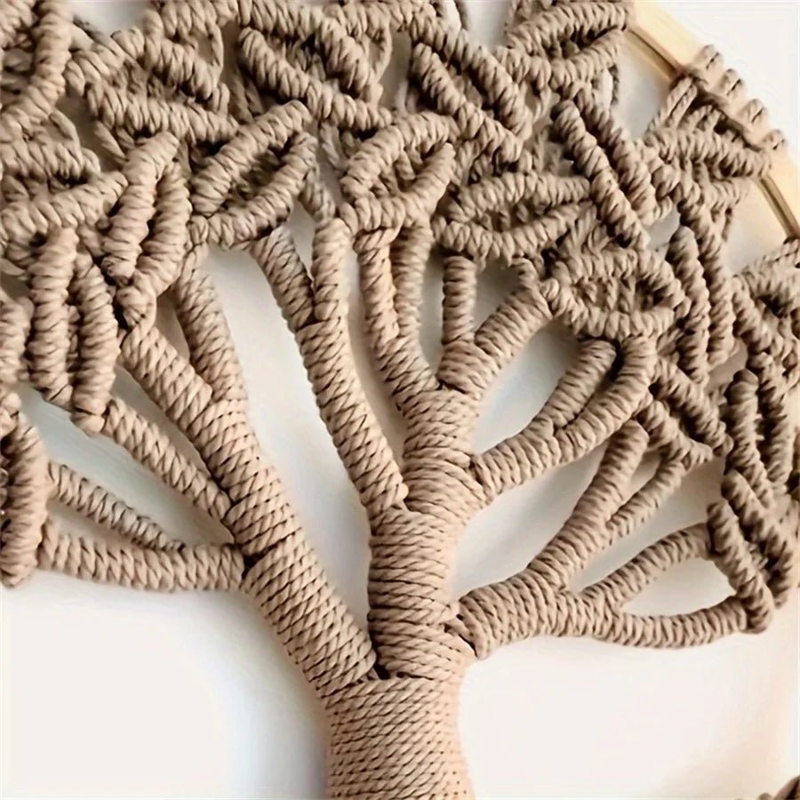 Un arbre de vie en macramé, méticuleusement noué avec une corde beige, est suspendu à un cercle de bois clair. Les détails complexes des branches et des feuilles créent une texture riche et un motif captivant. L'artisanat délicat du macramé apporte une touche naturelle et artistique à la pièce.