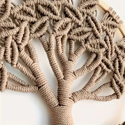 Un arbre de vie en macramé, méticuleusement noué avec une corde beige, est suspendu à un cercle de bois clair. Les détails complexes des branches et des feuilles créent une texture riche et un motif captivant. L'artisanat délicat du macramé apporte une touche naturelle et artistique à la pièce.