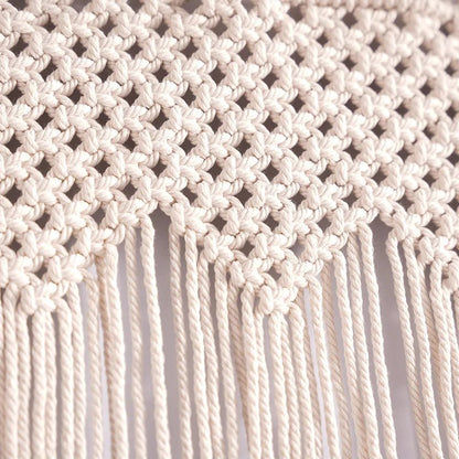 Gros plan détaillé d'un rideau en macramé ivoire.
Les nœuds complexes forment un motif de losanges aérés.
De longues franges pendantes ajoutent une texture douce et un mouvement subtil.