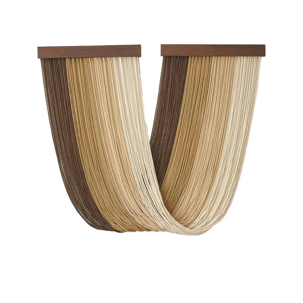 Une décoration murale en macramé présente des cordes beiges et marron clair suspendues à une barre en bois sombre. Les cordes forment un motif ondulé et drapé, créant une texture douce et un aspect artisanal. Cette pièce de macramé apporte une touche bohème et naturelle à un intérieur.