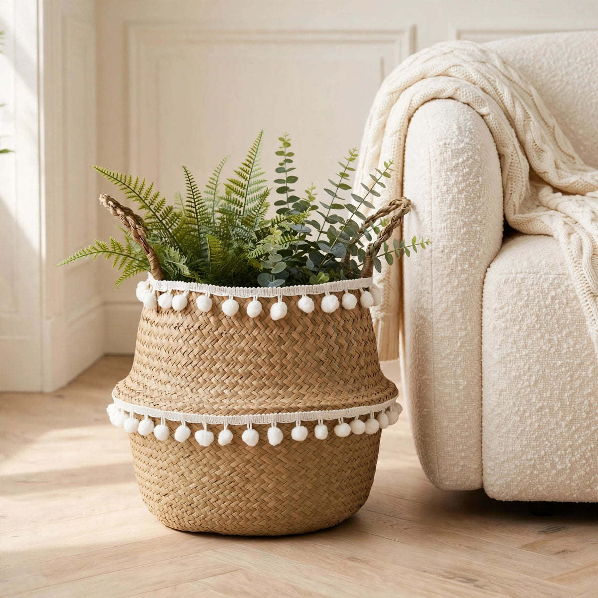 Panier en jonc de mer à franges au pied d'un fauteuil clair