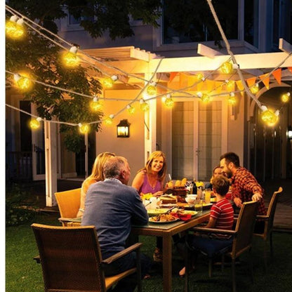 Une famille de six personnes profite dun repas au crépuscule autour dune table en plein air sous des guirlandes solaires dextérieur. Avec une protection IP44, la pergola blanche et léclairage de jardin Guirlandes solaire extérieur | EcoLume créent une atmosphère chaleureuse et accueillante.