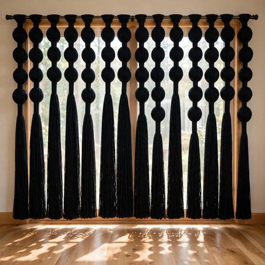 Rideau en macramé noir suspendu devant une fenêtre, lumière filtrée sur le parquet