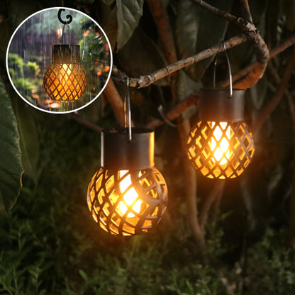 Deux lanternes solaires Mafrenesiedecoration Lanterne solaire | Flamme aux motifs en treillis sont suspendues aux branches des arbres, émettant une chaude lueur jaune-orange. Une image en médaillon en révèle une sous la pluie, soulignant sa résistance aux intempéries et son effet flamme qui ajoute du charme à léclairage extérieur.