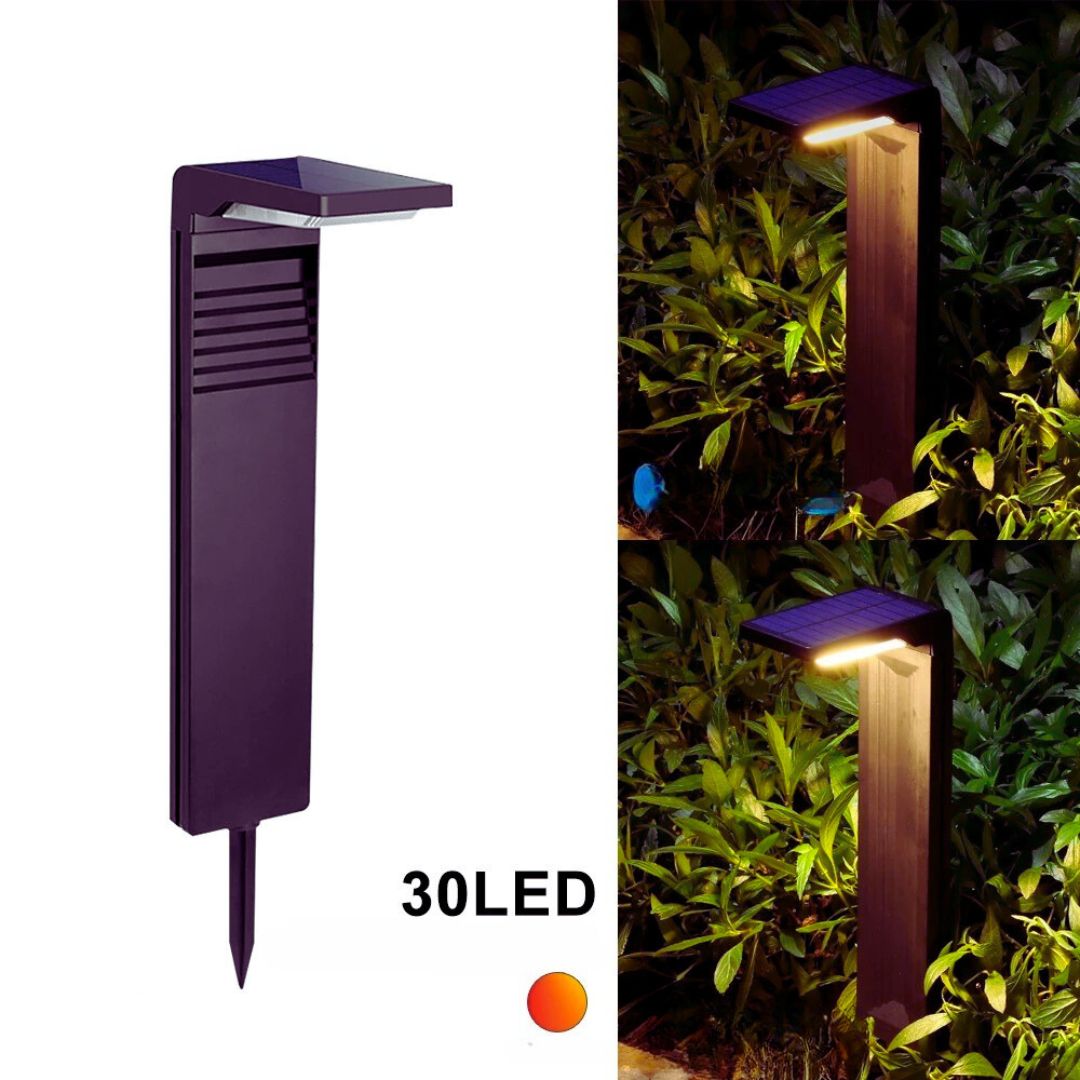 Une lampe solaire de jardin haut de gamme, noire et minimaliste, éclaire doucement un parterre de petites plantes vertes la nuit. La lumière blanche et brillante émane du sommet de la lampe, créant un contraste saisissant avec l'obscurité environnante. On aperçoit une bordure de jardin en pierre au premier plan, ajoutant une texture intéressante à l'image.