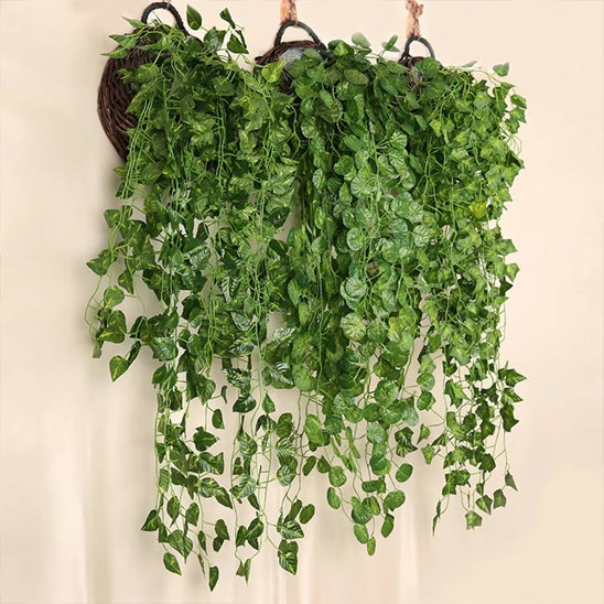 Trois paniers suspendus en osier ornent un mur clair.
De chaque panier débordent de luxuriantes plantes artificielles retombantes, créant un effet de cascade végétale.
Les feuilles vertes, de différentes formes et nuances, semblent réalistes.
Ces décorations apportent une touche de verdure sans nécessiter d'entretien.
L'ensemble offre une ambiance fraîche et naturelle à l'espace.