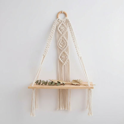 Étagère murale macramé avec plateaux bois accrochée sur mur blanc avec plantes