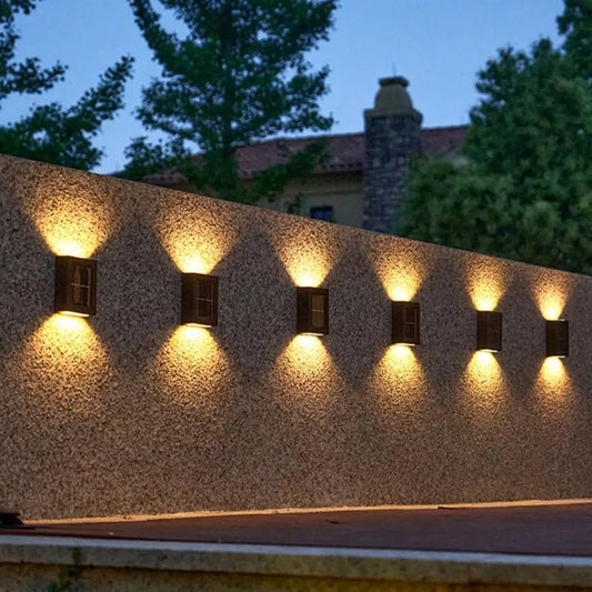 Cinq Lampe solaire jardin haut de gamme éclairent un mur de jardin au crépuscule.
